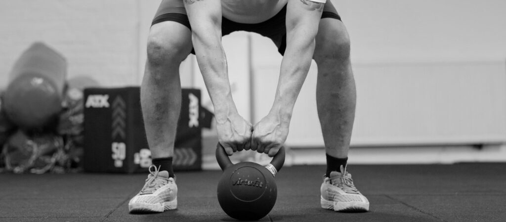 Kettlebell swing/hinge pozíció fekete-fehérben a PiroskaGymben Bükön, erőfejlesztéshez.
