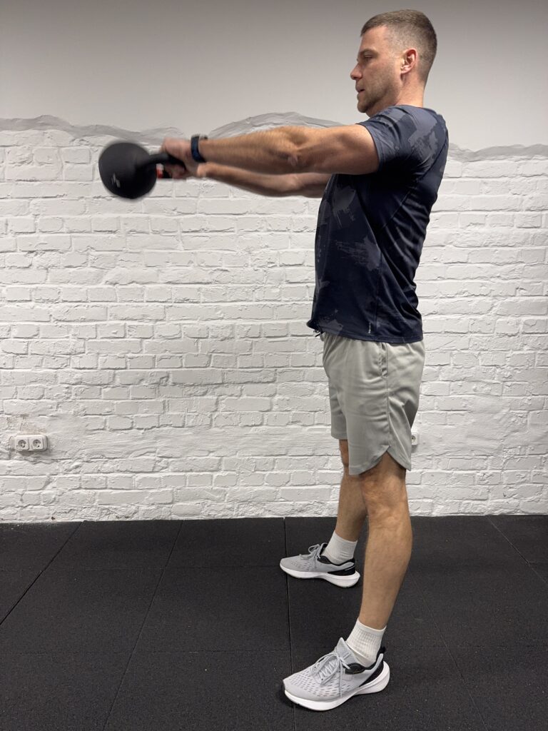 Kettlebell swing felső pozíció: karok nyújtva, törzs stabil, a bell mellkas magasságában.