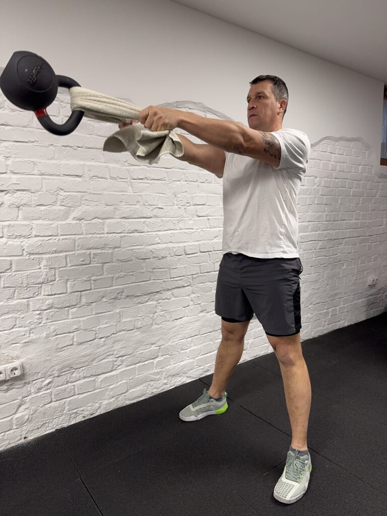 Törölközős kettlebell swing felső pozíció: a fogás és a törzs stabilitása nagyobb kihívást kap.